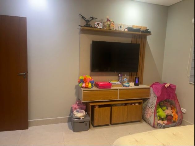 Quarto real: a parede da TV com brinquedos e a cômoda
